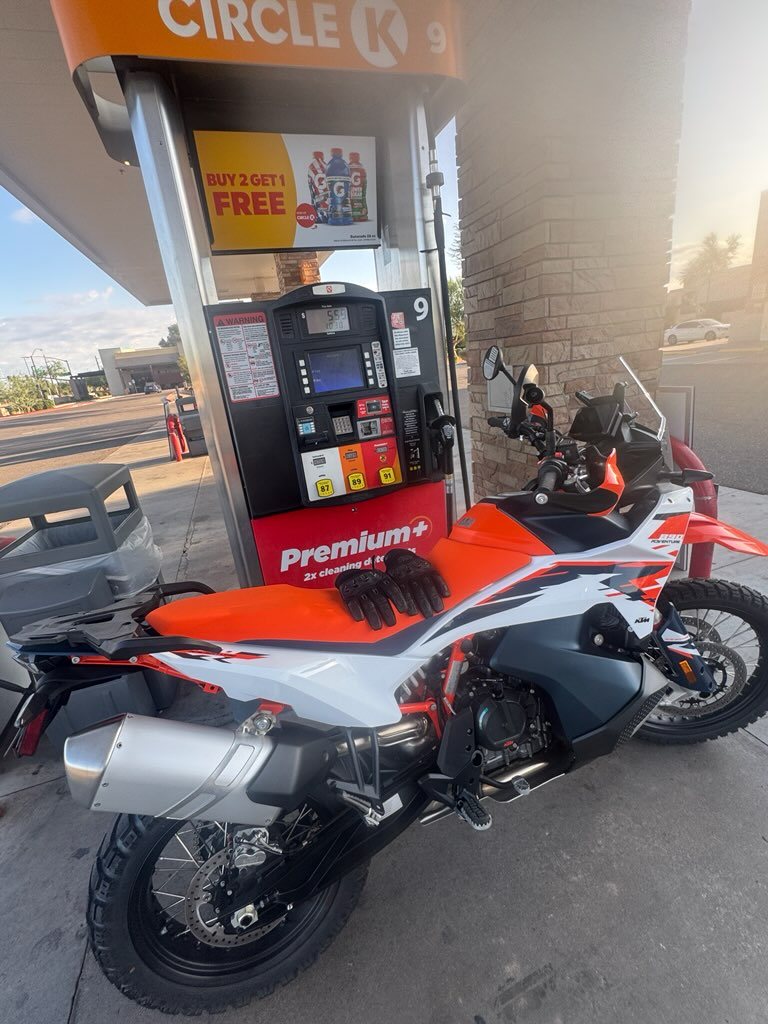 KTM 890 Adventure parked at a Circle K fuel pump with a luggage rack fitted at the rear and riding gloves resting on the seat